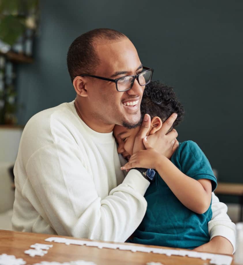 Loving father holding his son in an embrace on a chair